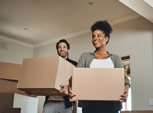 Couple holding moving boxes in a home
