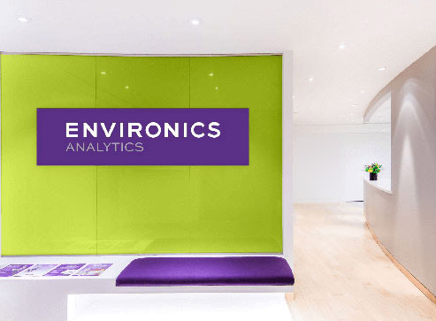 Environics Analytics office entryway with a green logo wall and a purple bench