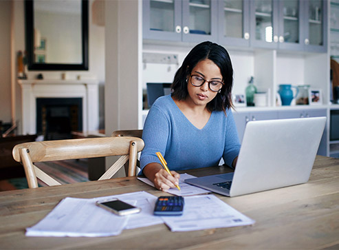 Woman sitting at a table and with a laptop and calculator