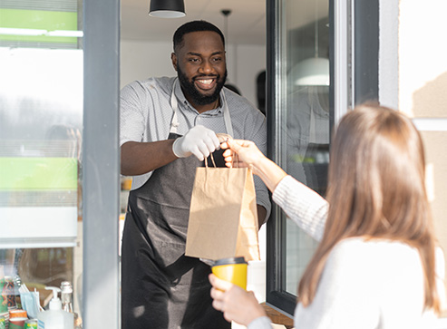 Drive-thru attendant handing a bag of food to customer