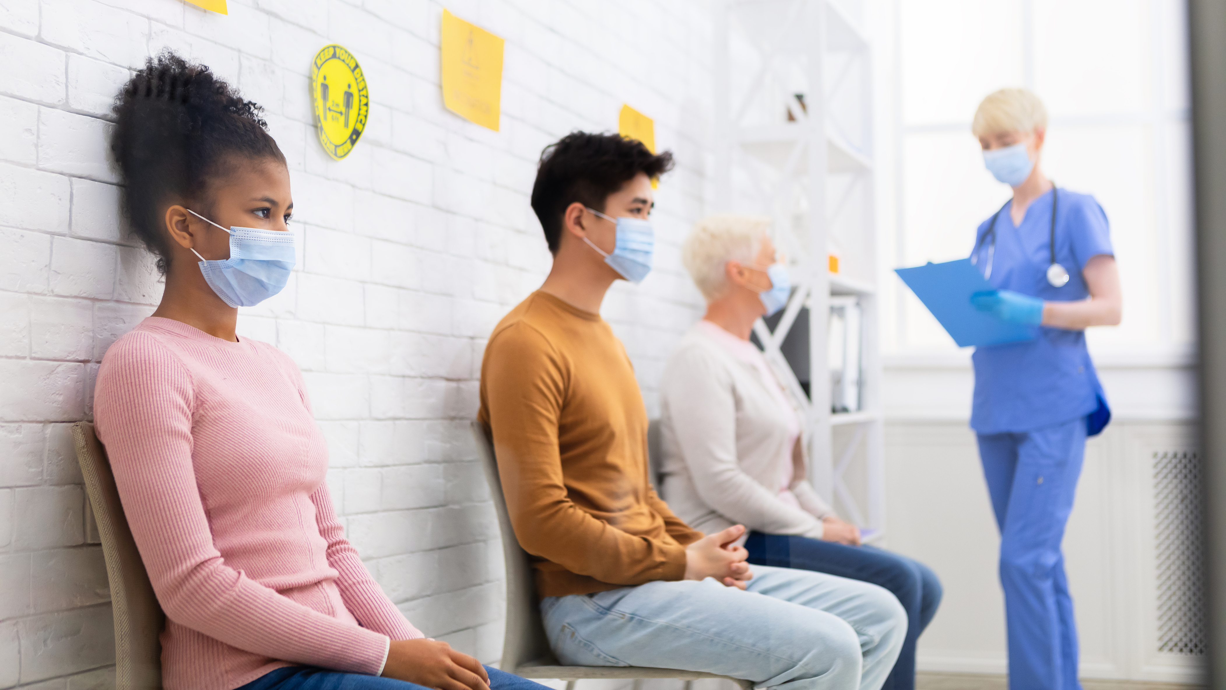 Seated patients wearing masks in the waiting area of a clinic