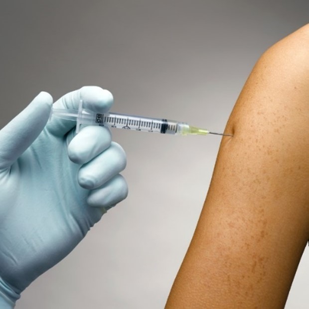 Hand with a syringe injecting into another person's arm