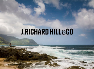 Ocean view with mountains and J. Richard Hill and Co logo in the centre of image