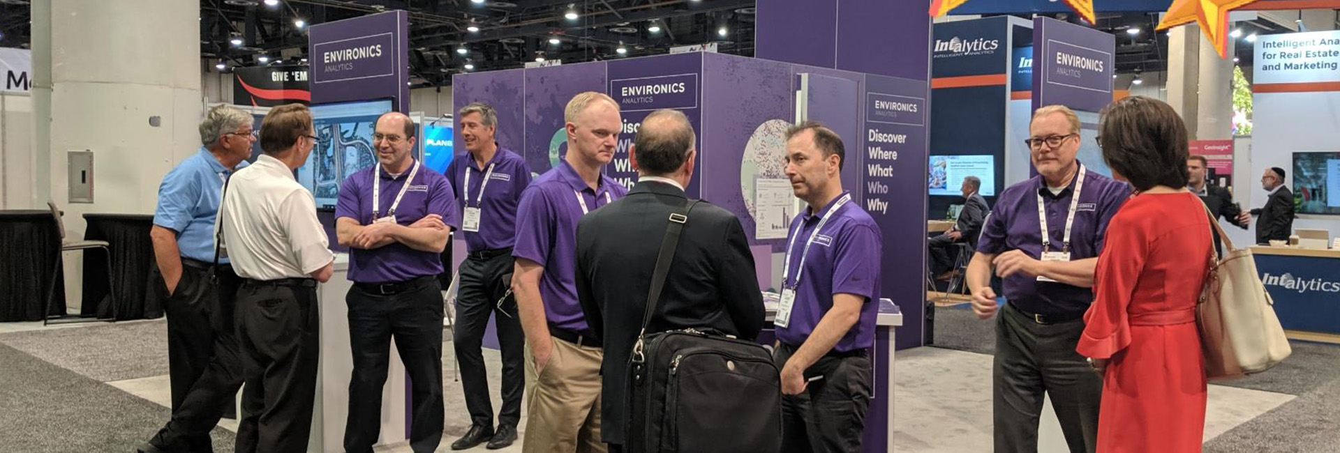 Group of people standing and talking to each other at an Environics Analytics event booth