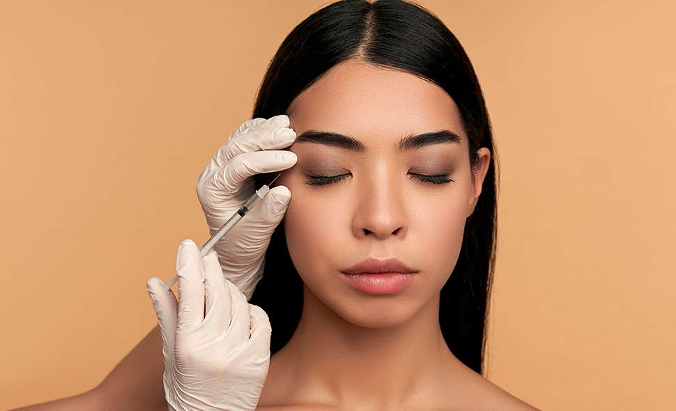 A young woman receiving a cosmetic injection near the eye brow