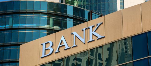 Modern glass office building with a large BANK sign, representing the banking industry