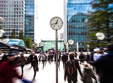 Large clock above a crowded public square with blurred people walking