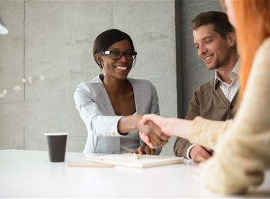 Two people shaking hands across a table, illustrating customer engagement
