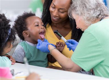 Female nurse examines young boy while his mother looks on