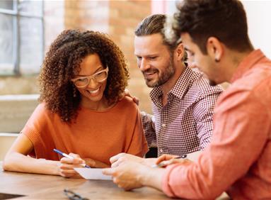 Three people reviewing a document together, illustrating data analytics to acquire more customers
