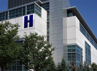 Hospital building with a large H sign, illustrating site location decisions for healthcare
