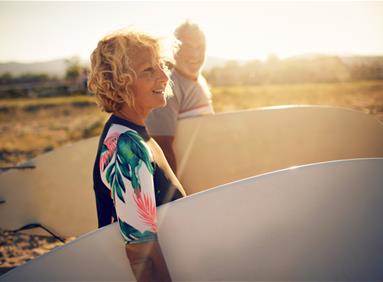 Person holding a surfboard on a beach, illustrating marketing return on investment in the travel industry