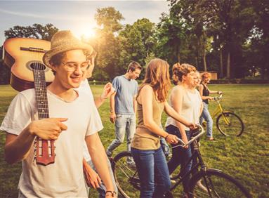 Group of young adults with bicycles and a guitar in a park, illustrating travel partnership opportunities