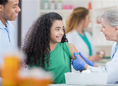 Pharmacist giving a vaccine to a girl while her father looks on, illustrating community wellness programs