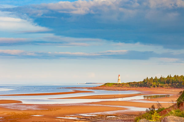 Lighthouse on a coastal shoreline at low tide under a blue sky on Canada's east coast