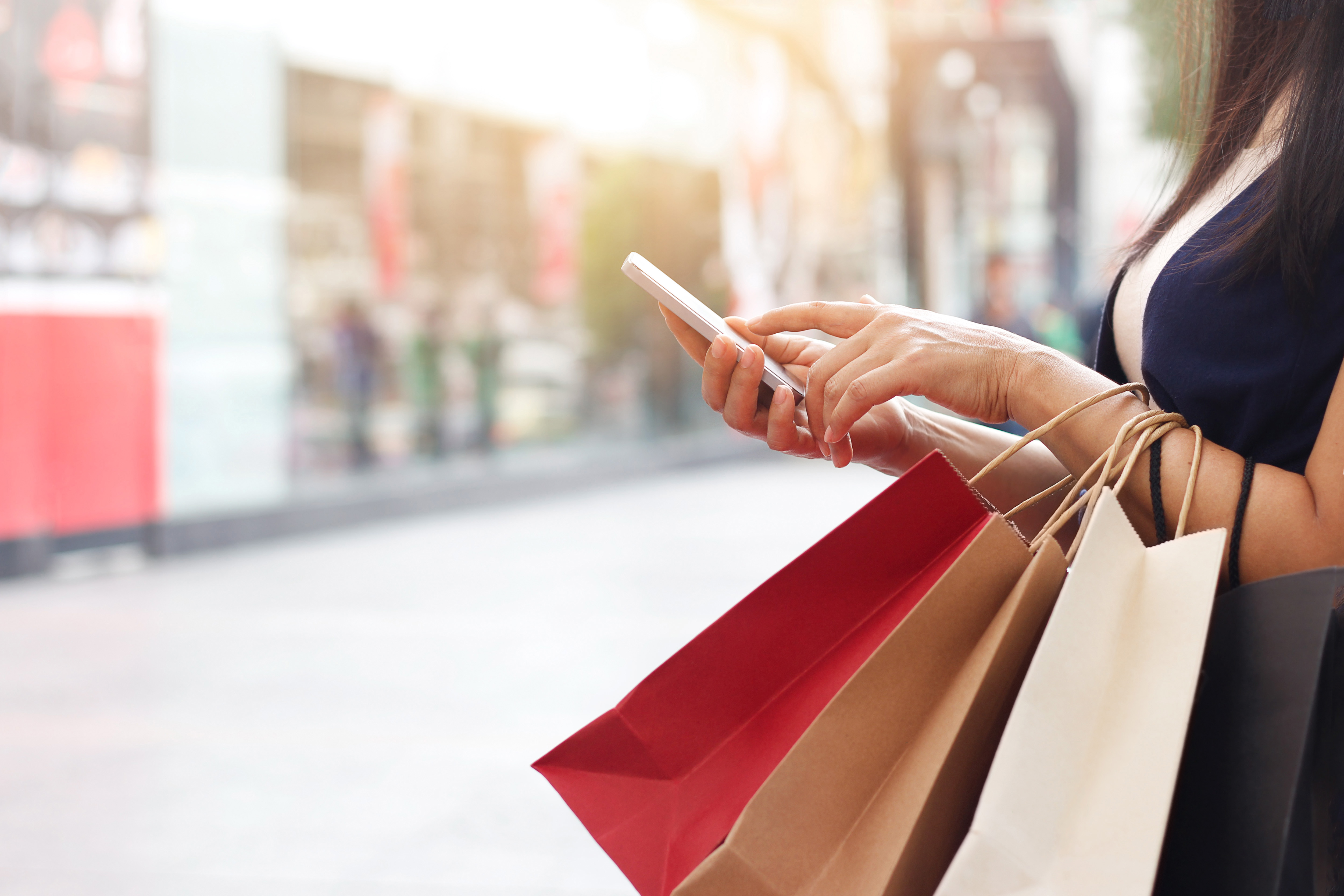 Woman's hands holding shopping bags and a smartphone