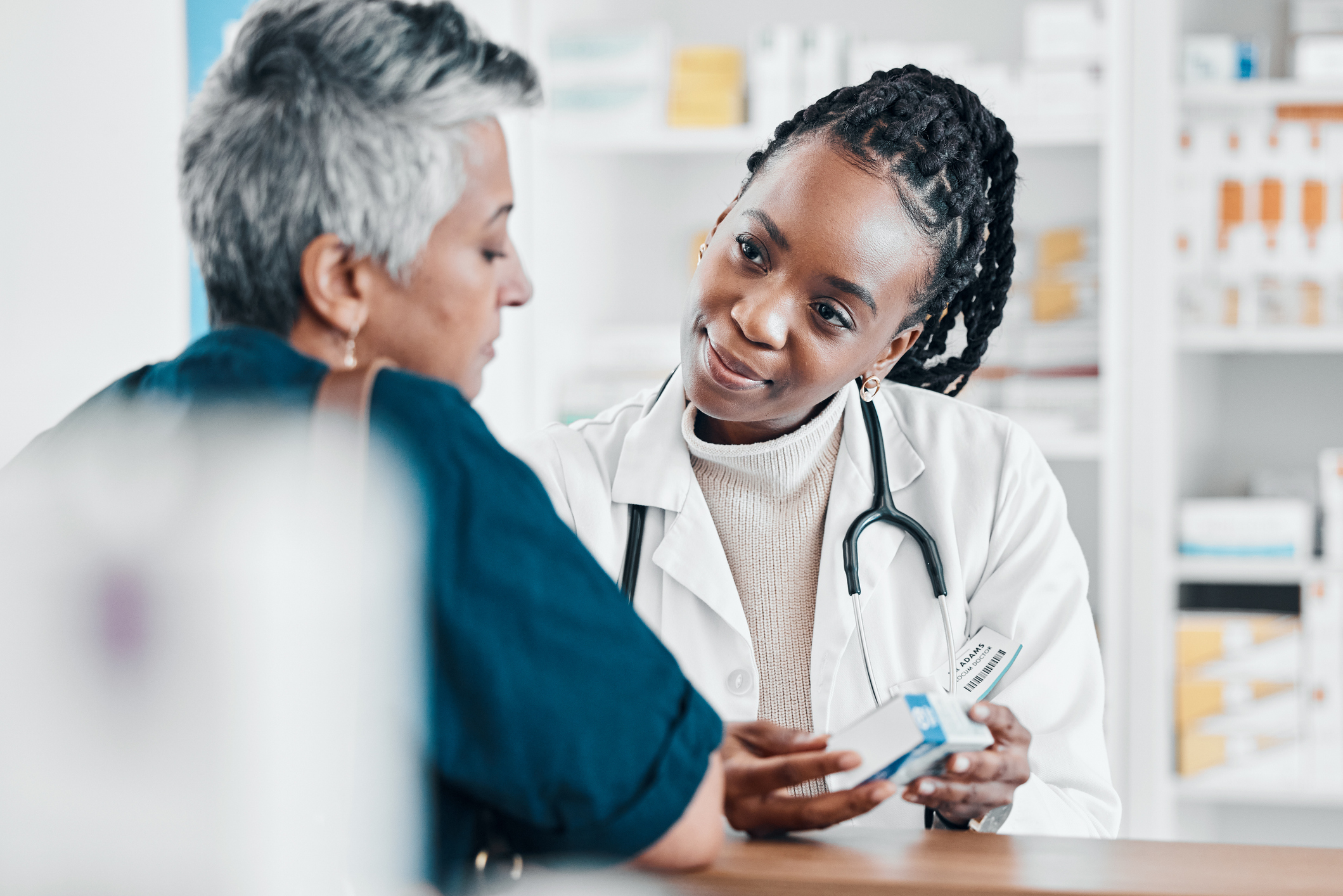 Pharmacist showing a medication box to a customer in a pharmacy, illustrating retail healthcare