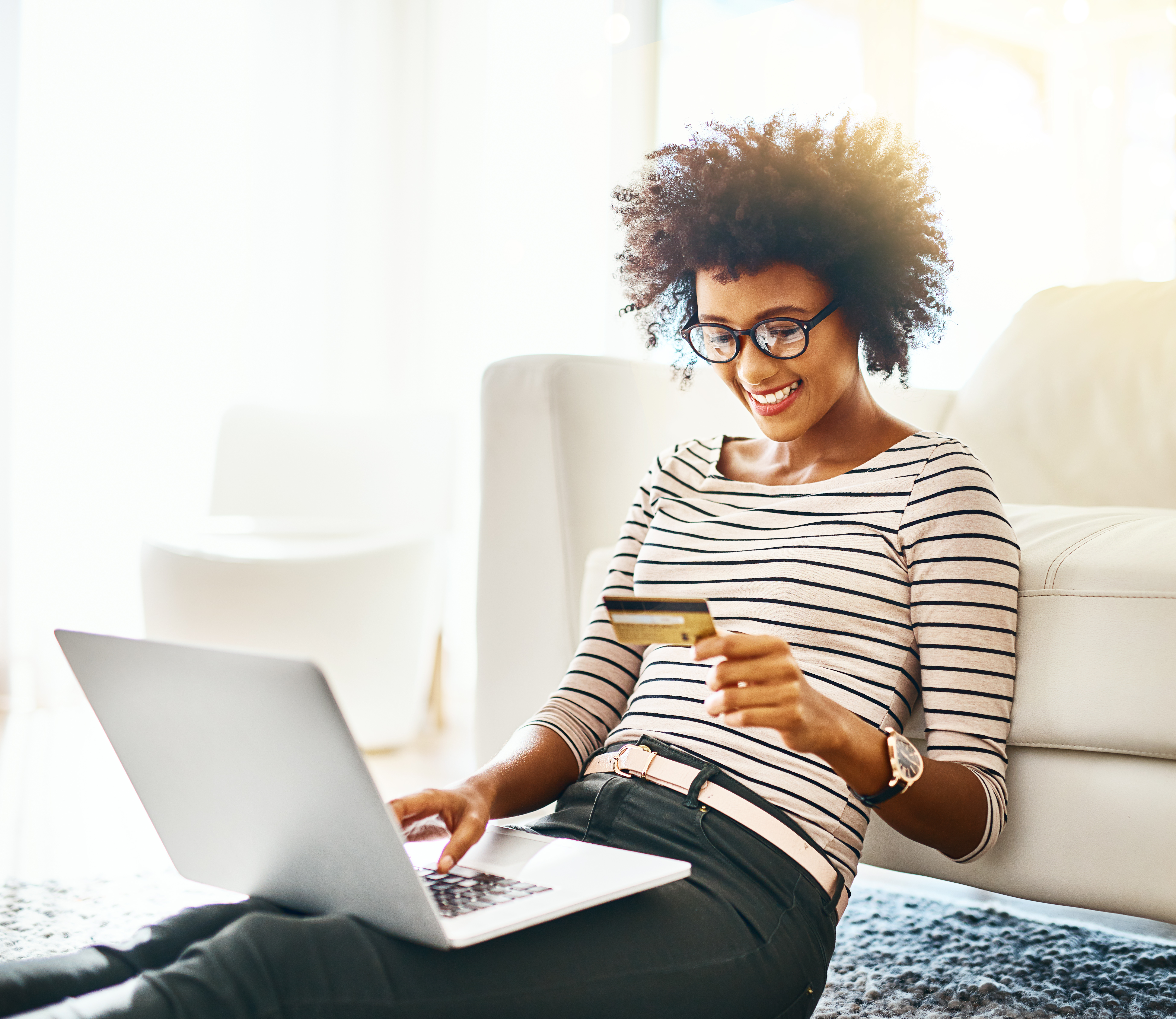 Woman holding a bank card while using laptop