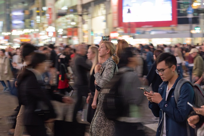 people in a crowd walking and looking at their phones